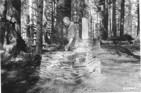 Man inspecting campground fireplace