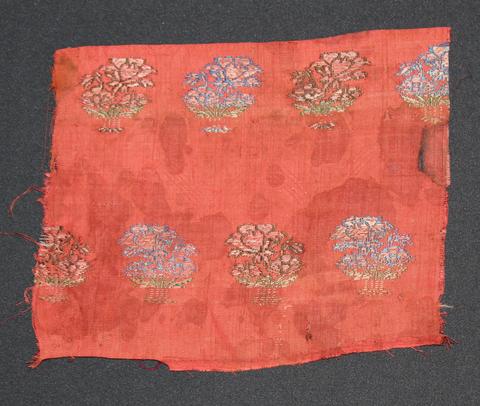 Textile fragment of rust-orange cotton brocaded with floral spray motifs
