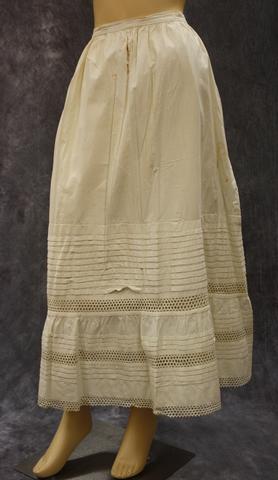 Petticoat of white cotton muslin with rows of tucks and alternating rows of rick rack at bottom half