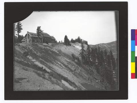 Crater Lake Lodge on rim of crater. Steep crater wall in foreground. (recto)