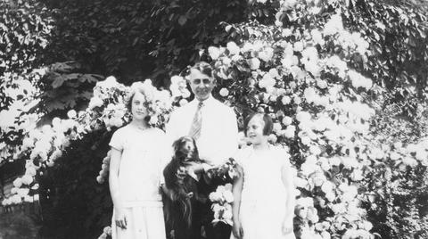 Walter Brown with daughters, Grace and Lois, and dog near rose bush