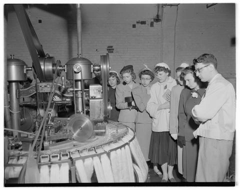 Home Economics students examining an industrial textiles machine on a field trip, April 1952